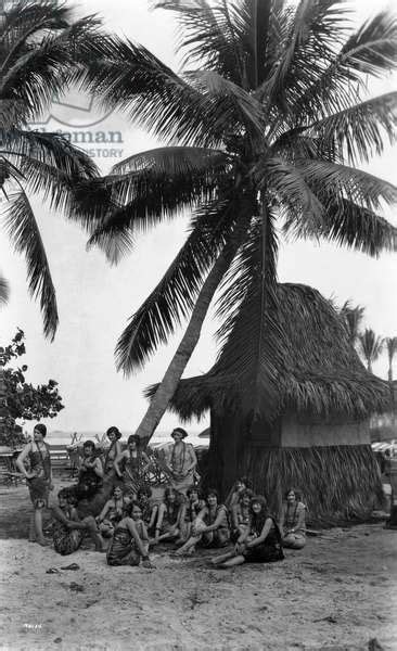 Young Women In Polynesian Flapper Costumes Lounge Under A Coconut Palm