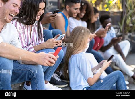 Young Multiracial Group Of Friends Using Mobile Smartphone Sitting On