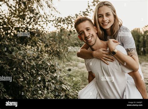 Portrait Of Young Smiling Couple Man Carrying Woman On Back Stock