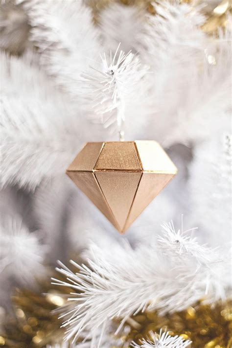 A Gold Ornament Hanging From A White Christmas Tree
