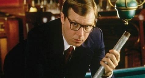 A Man In Glasses Leaning Over A Pool Table Holding A Stick And Looking
