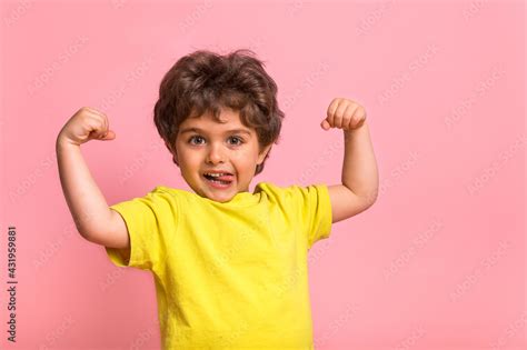 Funny Little Sportive Kid Boy In Yellow Shirt Showing His Muscles