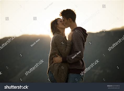 Romantic Young Couple Kissing Passionately At Sunset Mountains On
