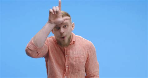 Medium shot of young man taunting at camera against blue background
