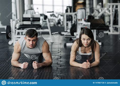 Young Muscular Couple Doing Doing Hard Workout At The Gym. Doing Plank In The Gym Stock Photo 