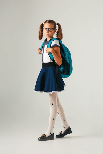 Premium Photo Cute Schoolgirl In Glasses With Blue Backpack Looking