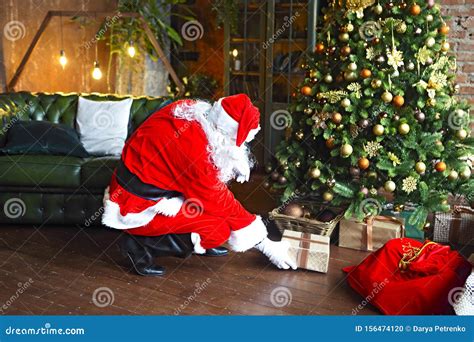 Santa Claus Secretly Putting Gift Boxes Under The Christmas Tree Stock Photo Image Of Lights