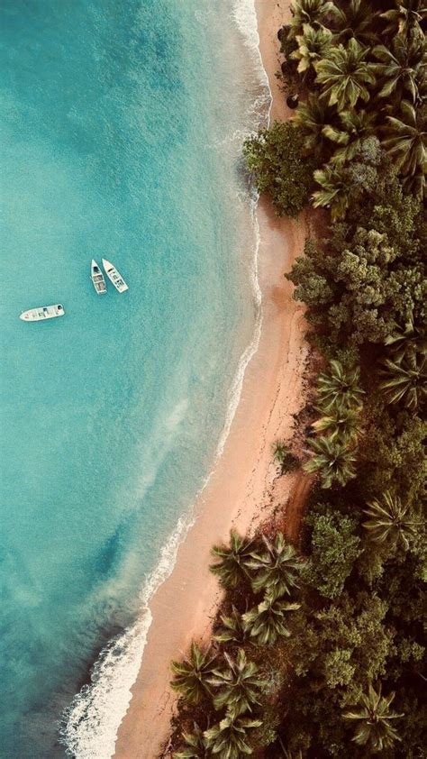 Two Boats Are In The Blue Water Near Some Palm Trees And White Sand On An Island