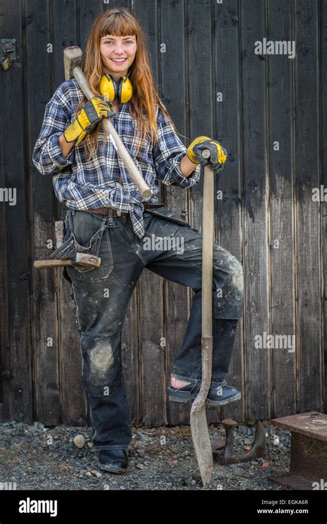 Girl In Construction Worker Clothings Standing With A Shovel And Hammer