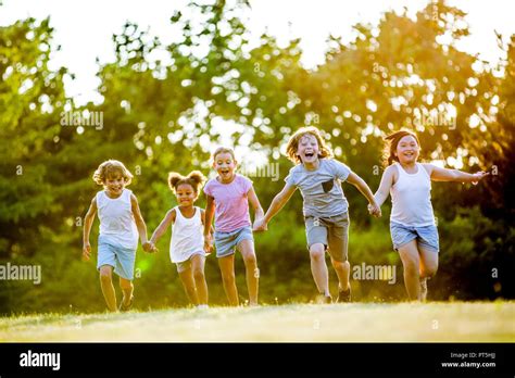 Children Holding Hands And Running In Park Laughing Stock Photo Alamy
