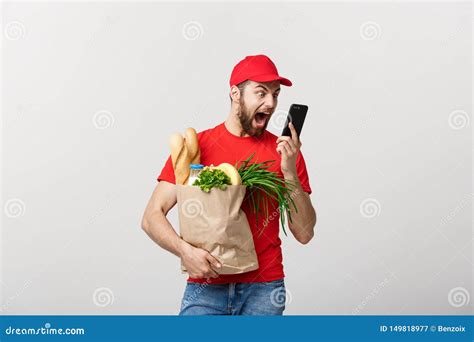 delivery concept handsome caucasian grocery delivery courier man in red uniform with grocery