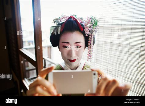A Woman Dressed In The Traditional Geisha Style Wearing A Kimono And Obi Taking A Selfie Of