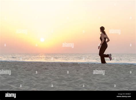 Woman Jogging On Beach At Sunrise Stock Photo Alamy