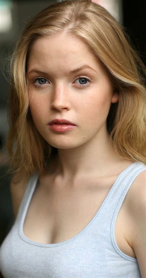 A Woman With Blonde Hair And Blue Eyes Is Posing For The Camera While Wearing A Tank Top