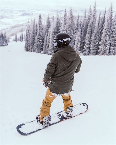 foto de persona con chaqueta marrón y pantalones naranjas montando palas de esquí en terreno