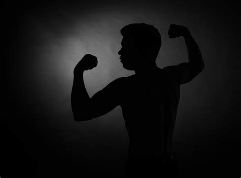 Premium Photo Silhouette Of Man Flexing Muscles Against Black Background