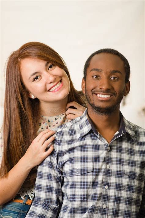 Interracial Charming Couple Wearing Casual Clothes Sitting On Wooden