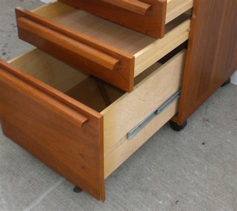 Unmarked, the cabinet is made of pressed wood with a teak veneer. Teak File Cabinet on Wheels For Sale at 1stdibs