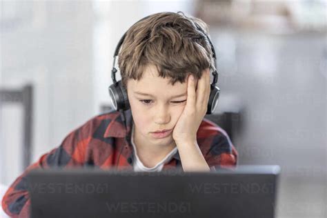 Boy Getting Bored During Online Classes Attending At Home Stock Photo