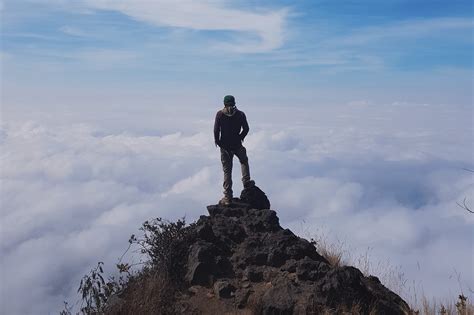 Man Standing On Cliff With Sea Of Clouds Background The Tribe