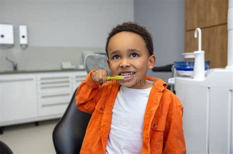 African American Boy Looking Involved While Brushing His Teeth Stock