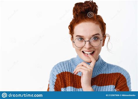 close up portrait of excited redhead girl in glasses listening to interesting story biting lip