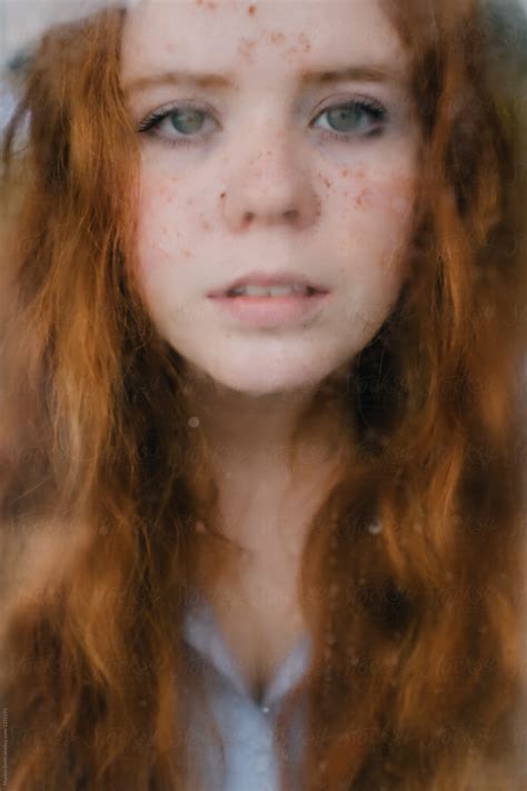 Close Up Of A Ginger Haired Teenager Looking Out Of A Rainy Window By Stocksy Contributor