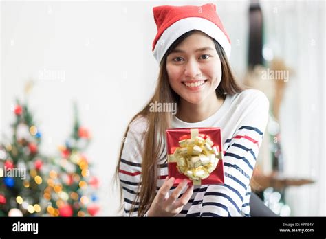 asia woman smile holding gold xmas t box at holiday party with decoration flag at background
