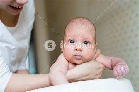 Unrecognizable Mother Holding Her Baby Son Bathing Him In Small White