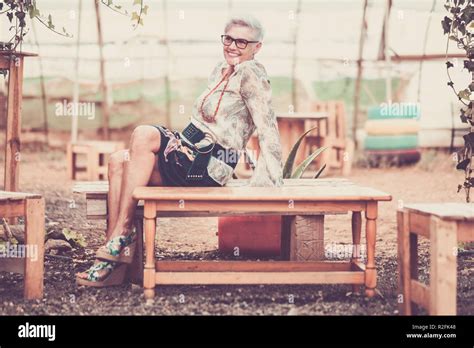 Mature Senior Adult Woman Sitting And Smiling On A Wood Recycled Bench