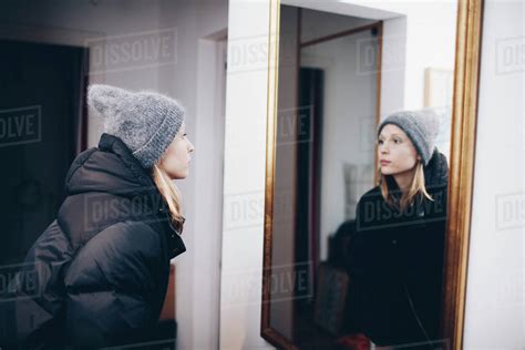 Woman Looking At Reflection In Mirror On Wall Stock Photo Dissolve