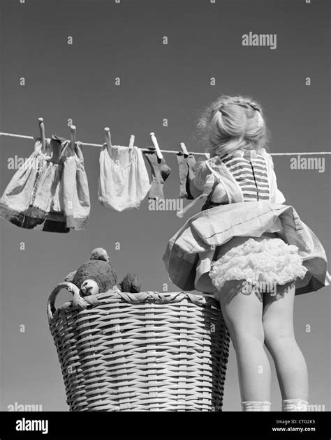 1950s Back View Of Girl Hanging Laundry Wind Blowing Skirt To Show