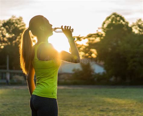 Runner Woman Drink Water In Stadium Exercising Outdoors Fitness Tracker