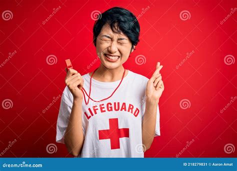 Young Beautiful Asian Lifeguard Girl Wearing T Shirt With Red Cross Using Whistle Gesturing