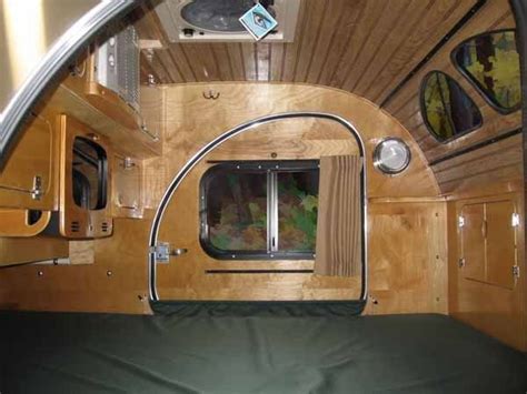 The Interior Of A Small Camper With Wood Paneling And Green Bedspread