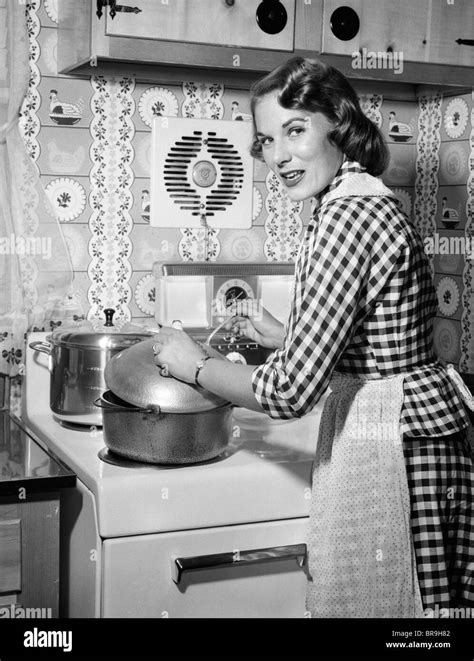 1950er Jahre Hausfrau TrÄgt Karierte Kleid Stehend In KÜche RÜhren Topf