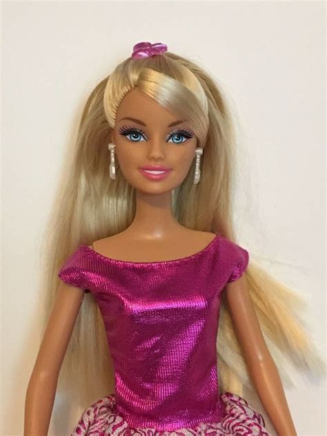 A Barbie Doll With Blonde Hair Wearing A Pink Dress