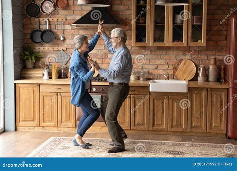 Energetic Middle Aged Family Couple Dancing In Kitchen Stock Photo