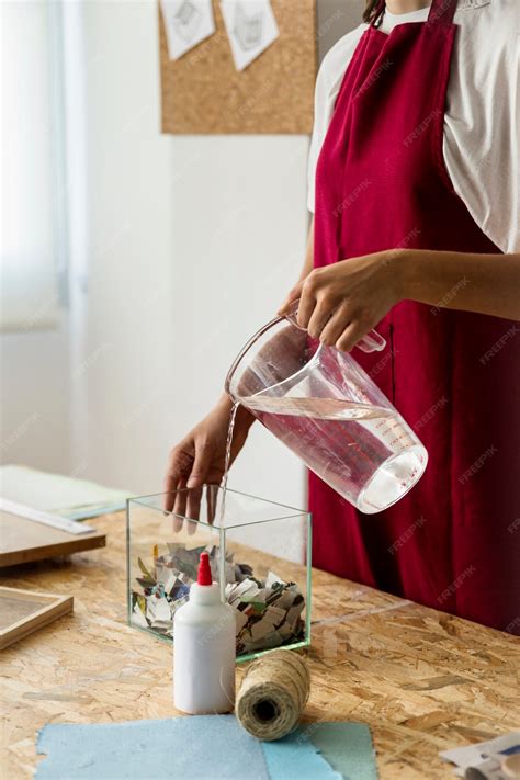 Free Photo Woman Pouring Water Into Glass Container With Torned Paper