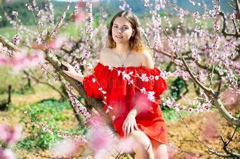 Cheerful Girl Posing In A Red Dress In Spring Blooming Garde Stock