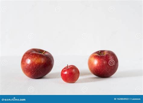Tow Parent Apples With A Baby Apple On Red Background Stock Photo