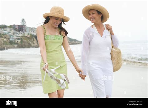 Mother And Daughter Walk Along Beach Holding Hands Stock Photo Alamy