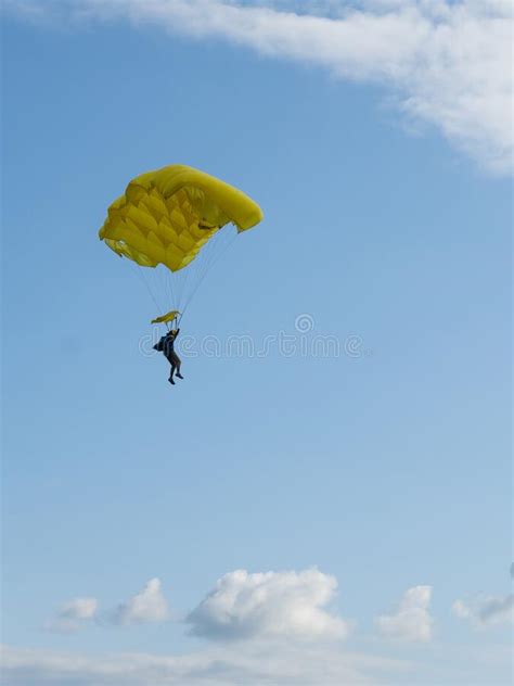 Parachuter Descending With Parachute Against Blue Sky Skydiver In The
