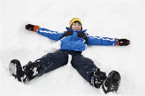 Young Boy Making Snow Angel On Slope — Stock Photo © Monkeybusiness