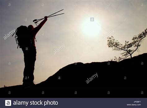 Silhouette Of Happy Tourist With Poles In Hand Above Head Sunny