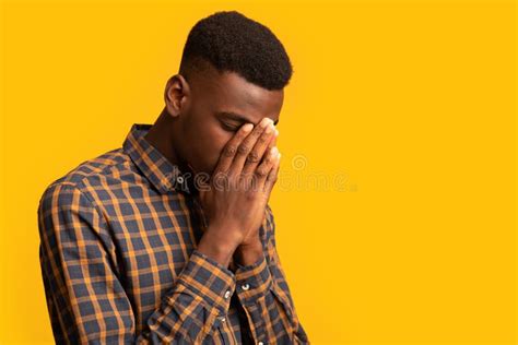 Upset Black Guy Covering Face With Two Hands In Despair Stock Image