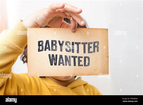 Caucasian toddler hand holding a yellowed flyer with Babysitter wanted