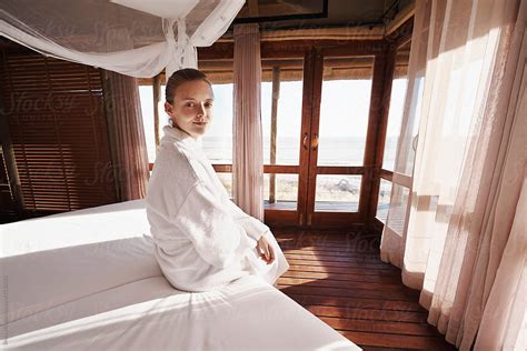 Young Woman In A Bathrobe Sitting On The Bed Of Her Hotel Room By