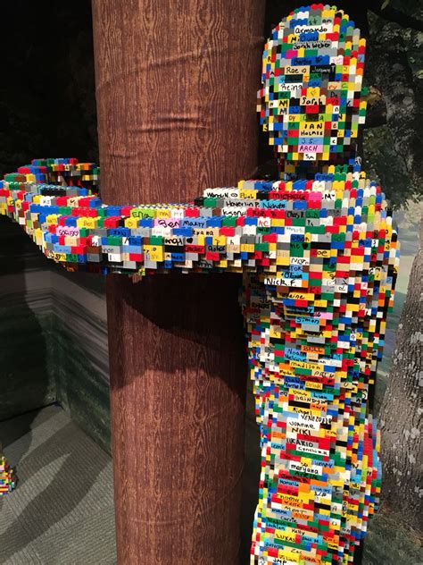 A Sculpture Made Out Of Legos Sitting On Top Of A Wooden Pole Next To A