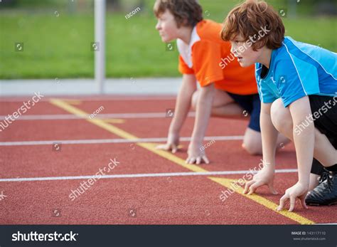 Side View Of Male Runners On Starting Position At Racetrack Stock Photo